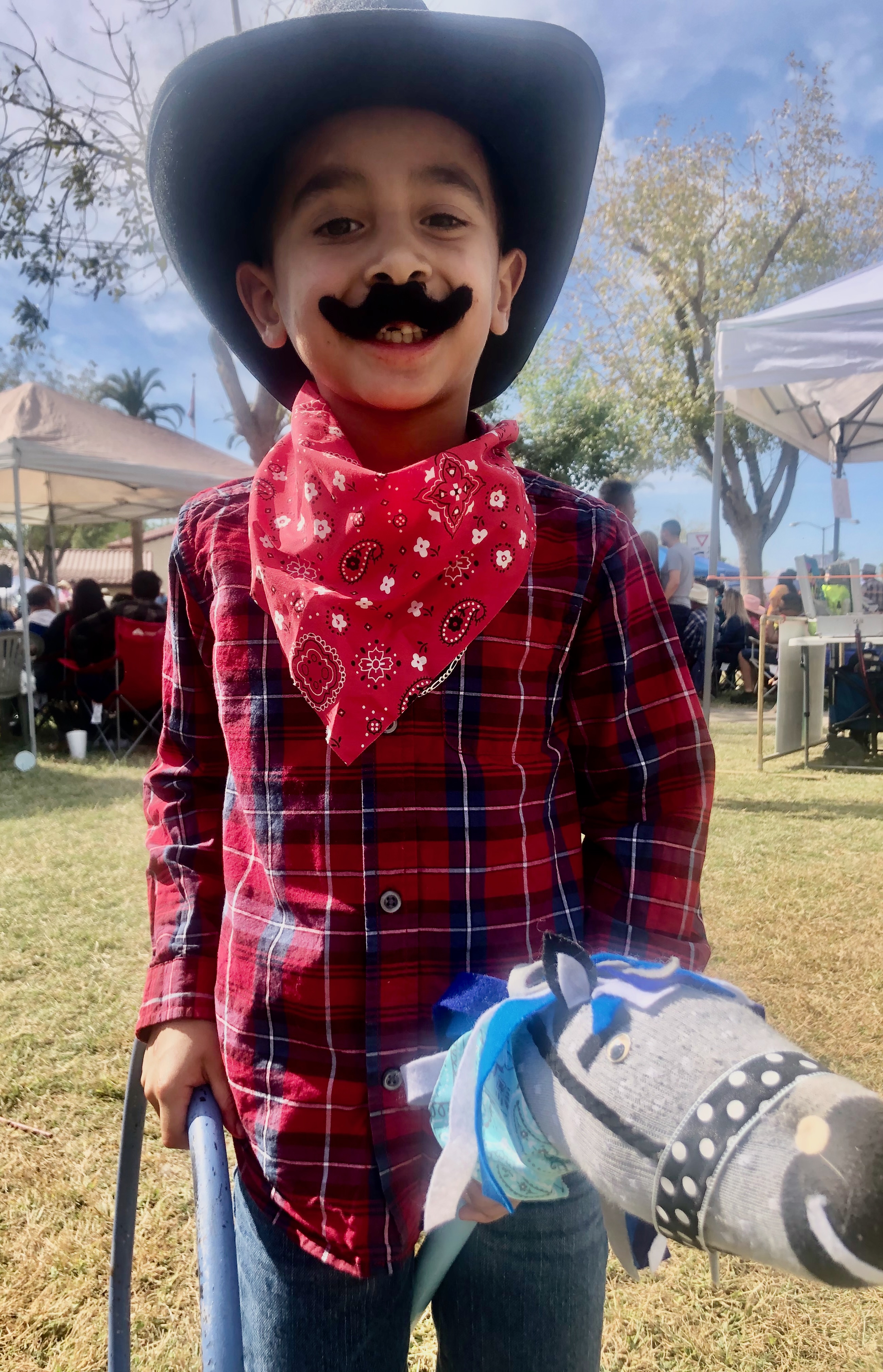 Adorable little cowboy with hat, mustache and stick pony at Sunshine Hoops rodeo party