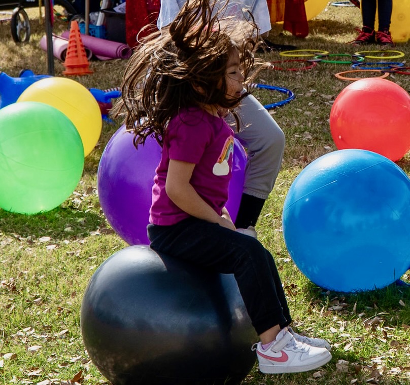Young girl bouncing on a handled hopper ball at a Sunshine Hoops event
