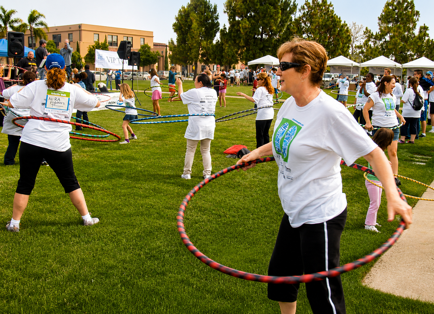 Large group of adults hooping together at an outdoor health and wellness community event