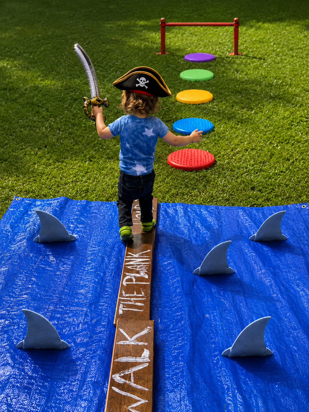 Little pirate walking the plank surrounded by shark fins at a Sunshine Hoops pirate party